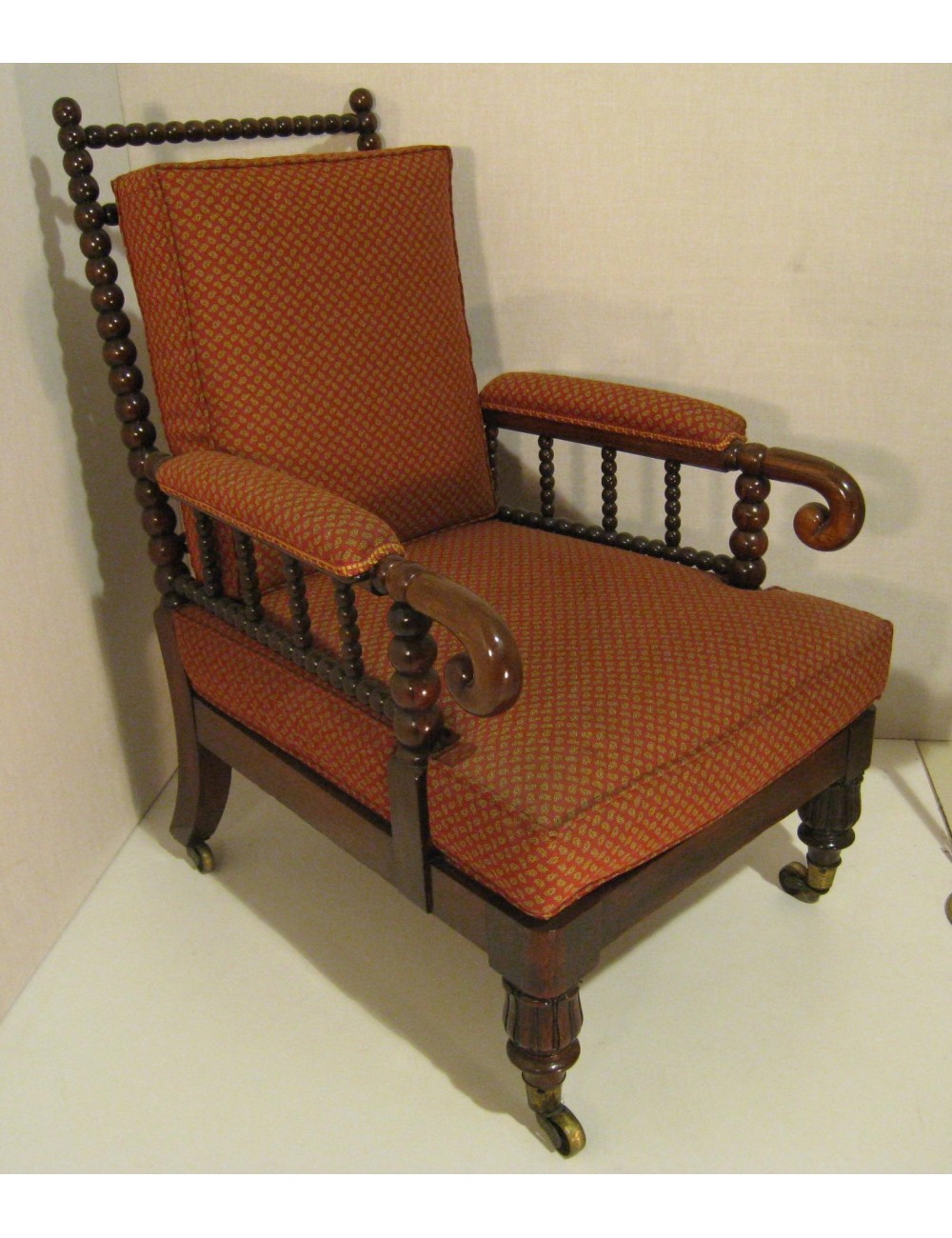 Poltrona Vittoriana in legno di mogano con parti tornite e rotelle, sedile e schienale con cuscini. Braccioli imbottiti. Poltrona Vittoriana in legno di mogano con parti tornite e rotelle, sedile e schienale con cuscini. Braccioli imbottiti.