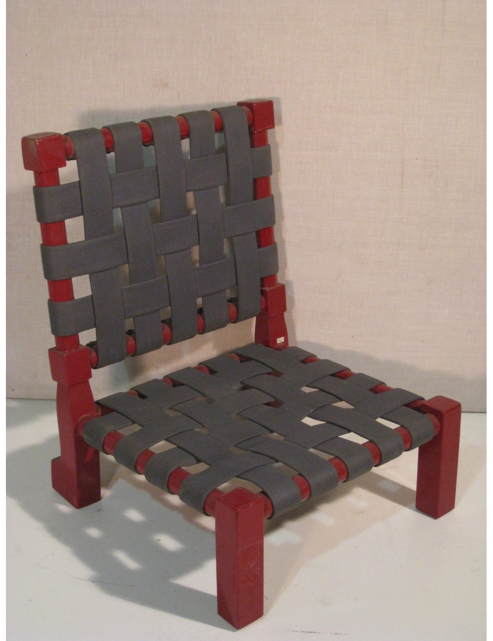 Sedia bassa laccata rossa, con sedile e schienale con cinghie intrecciate Sedia bassa laccata rossa, con sedile e schienale con cinghie intrecciate